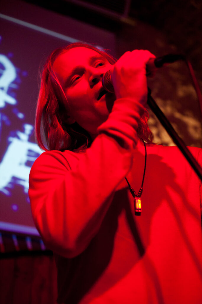 Efrem Wilder singing into a microphone under red stage lighting